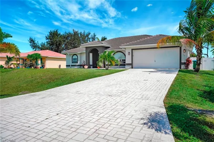 Mediterranean / spanish house featuring a front lawn, stucco siding, driveway, a tile roof, and a garage