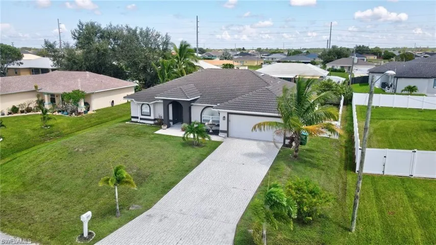 View of front facade with driveway, a tile roof, a garage, and a front lawn