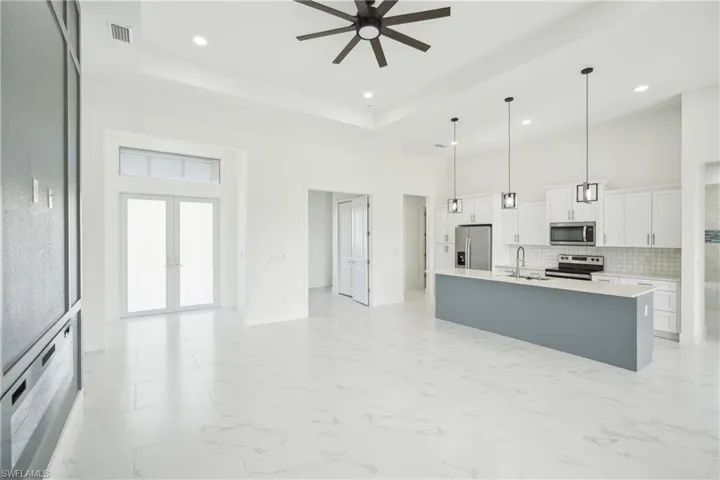 Kitchen featuring visible vents, ceiling fan, stainless steel appliances, a sink, and a high ceiling