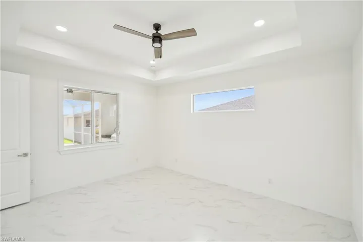 Unfurnished room with a tray ceiling, baseboards, marble finish floor, and recessed lighting
