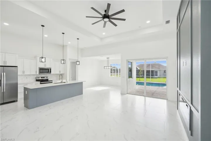 Kitchen with open floor plan, tasteful backsplash, a sink, a ceiling fan, and appliances with stainless steel finishes