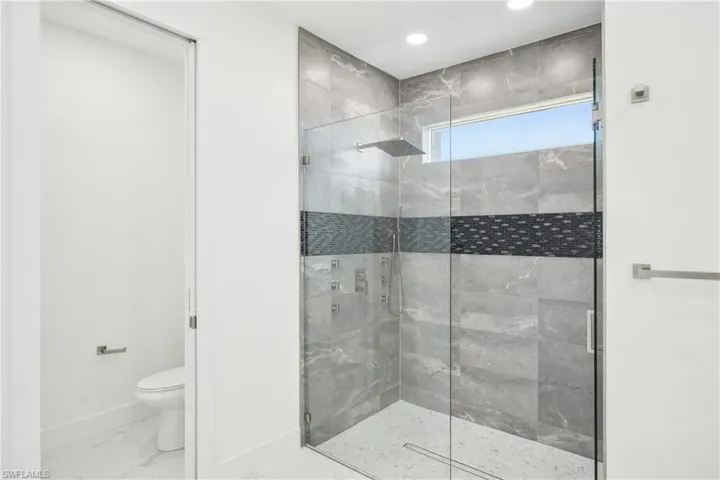 Full bath with a shower stall, baseboards, marble finish floor, and toilet
