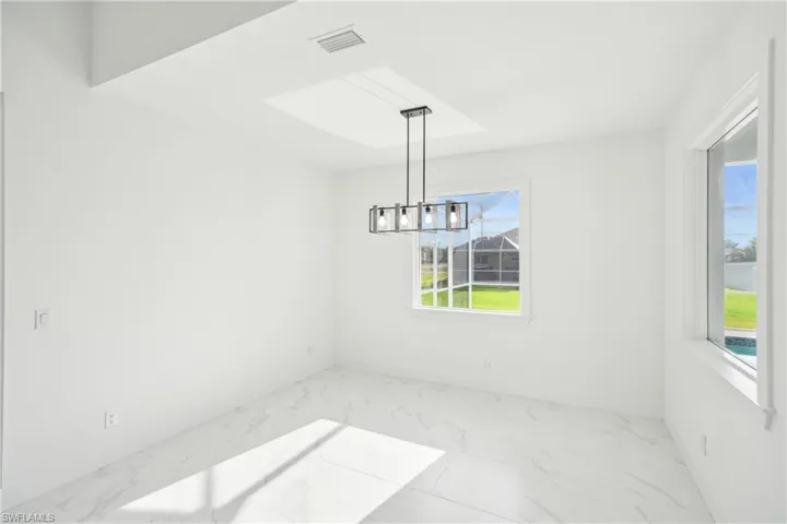 Unfurnished dining area with marble finish floor, a wealth of natural light, visible vents, and a chandelier