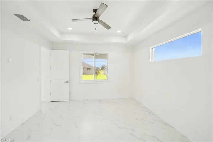 Unfurnished room featuring marble finish floor, recessed lighting, a raised ceiling, and visible vents