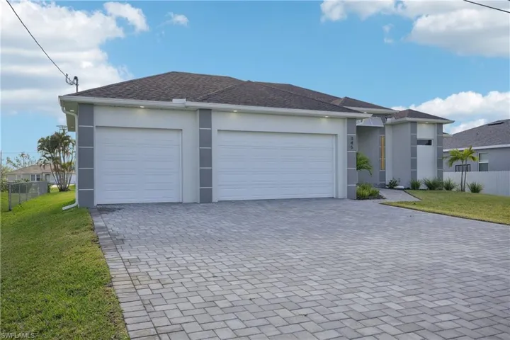 View of front of house featuring driveway, an attached garage, a front lawn, and stucco siding