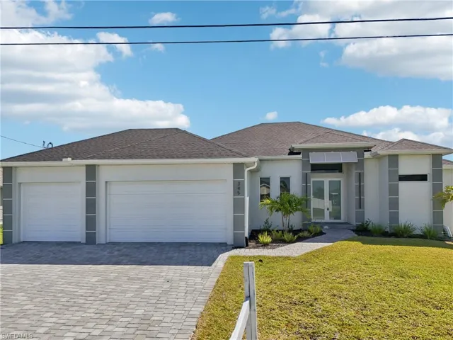 View of front of property featuring decorative driveway, an attached garage, a front yard, stucco siding, and french doors