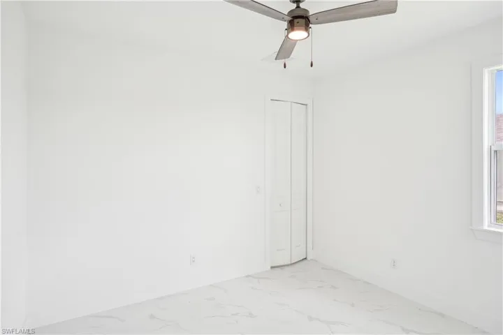 Spare room featuring marble finish floor, baseboards, and ceiling fan