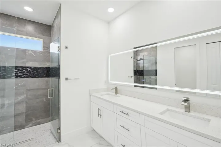 Full bathroom featuring marble finish floor, double vanity, a sink, and a shower stall