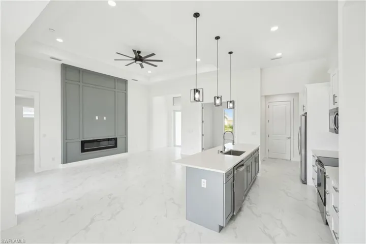 Kitchen with stainless steel appliances, recessed lighting, a center island with sink, a sink, and a tray ceiling