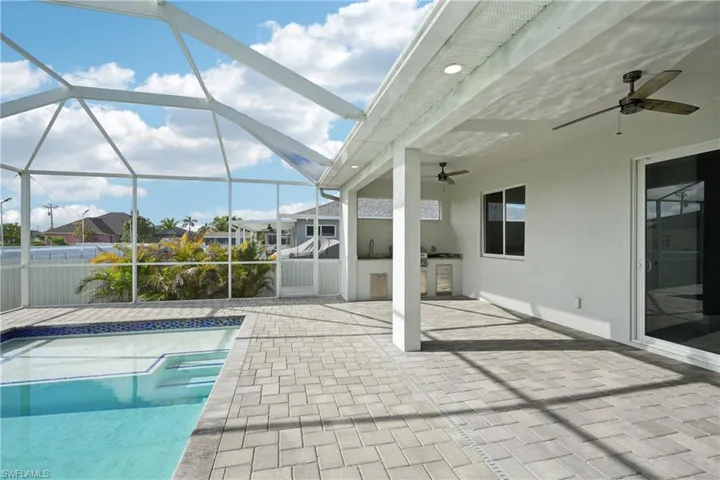 Pool with a lanai, an outdoor kitchen, a patio area, and a ceiling fan