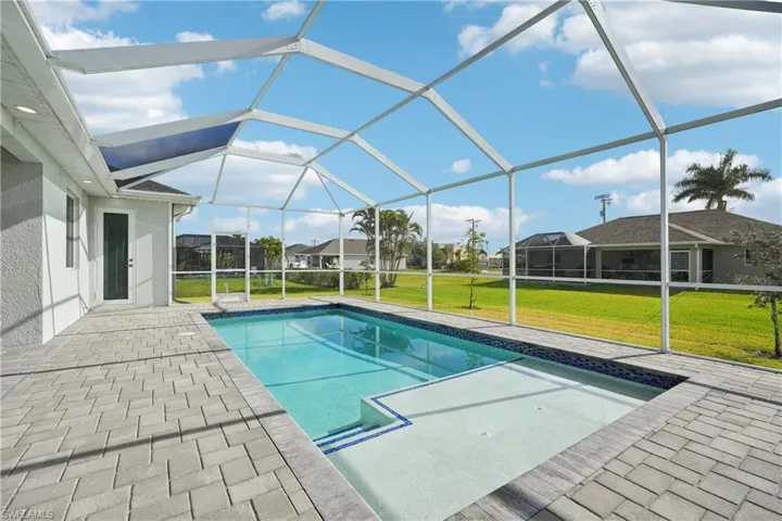 Pool with glass enclosure, a yard, and a patio area