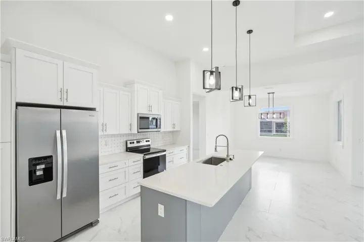 Kitchen with a sink, white cabinetry, tasteful backsplash, appliances with stainless steel finishes, and marble finish floor
