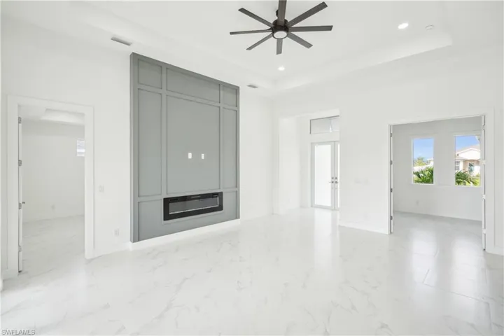 Unfurnished living room with a tray ceiling, visible vents, recessed lighting, and a ceiling fan