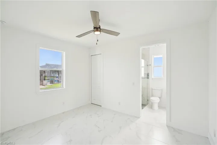 Unfurnished bedroom featuring baseboards, marble finish floor, a closet, and ensuite bath