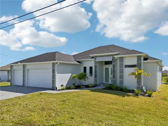 View of front facade with stucco siding, a garage, a front yard, and decorative driveway