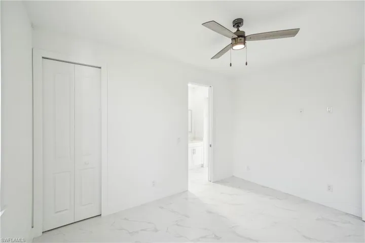 Unfurnished bedroom with marble finish floor, a closet, ensuite bathroom, and baseboards