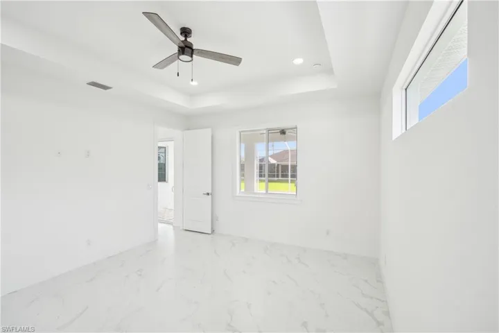 Spare room featuring plenty of natural light, visible vents, ceiling fan, and a tray ceiling