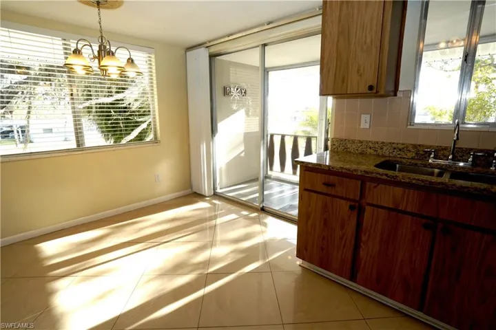 Kitchen with dark stone counters, decorative backsplash, hanging lights, and wood finish cabinetry