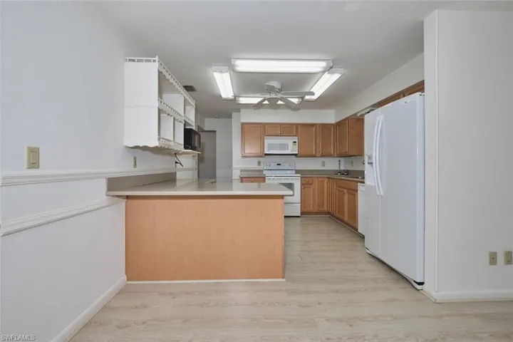 Very versatile kitchen.  White appliances, room for 3 barstools and new flooring.  There is a window/passthrough overlooking the pool and yard.