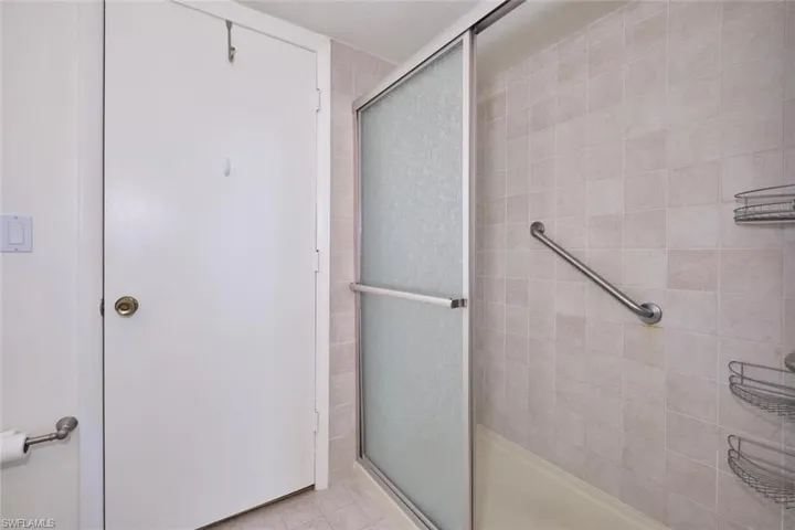 Nicely tiled shower with glass sliding doors.