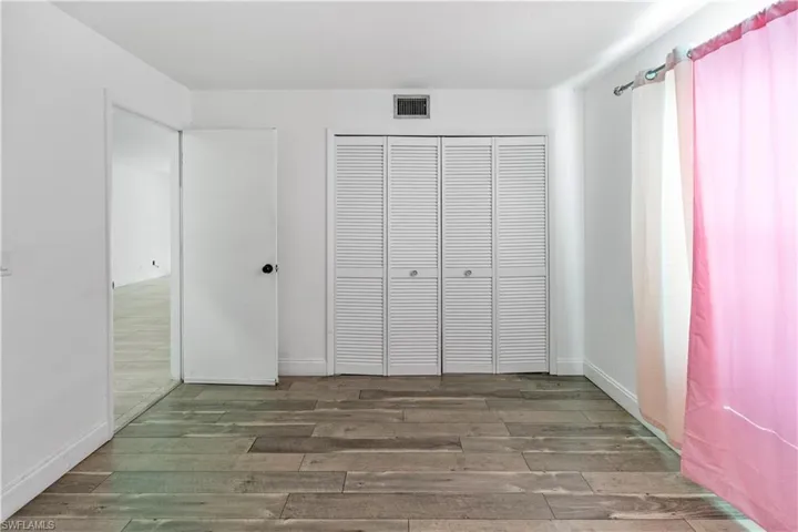 Unfurnished bedroom with dark wood-style flooring and a closet