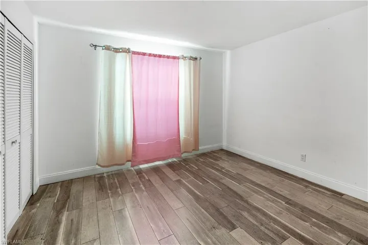 Unfurnished bedroom with wood finished floors and a closet