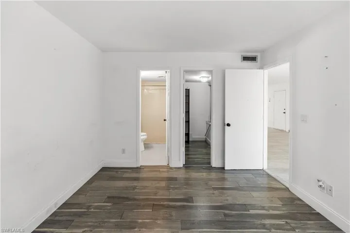Unfurnished bedroom featuring dark wood-style floors and ensuite bathroom