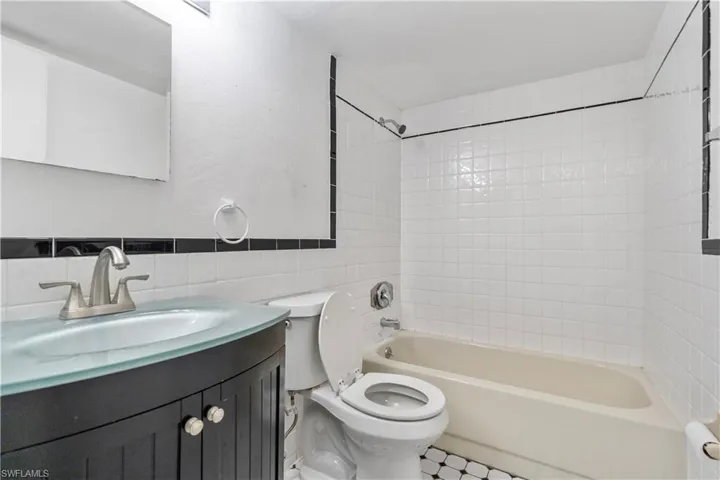Bathroom with vanity, tile walls,  shower combination, and wainscoting