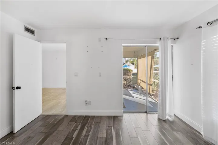 Empty room featuring dark wood-style flooring and baseboards