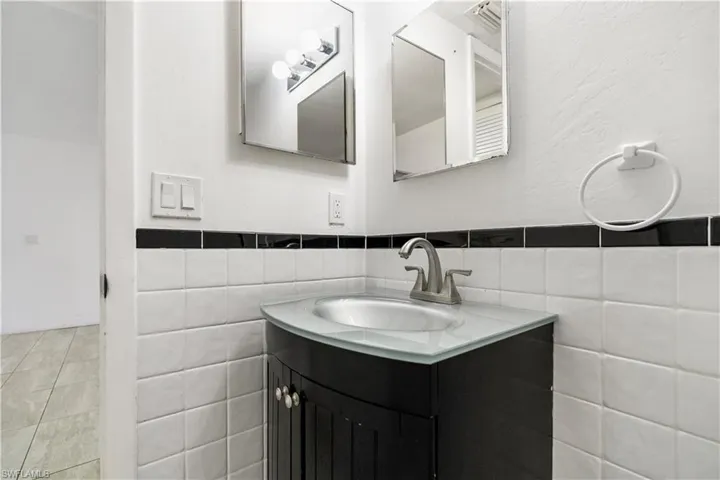 Bathroom featuring vanity, tile walls, wainscoting, tile patterned floors, and a textured wall