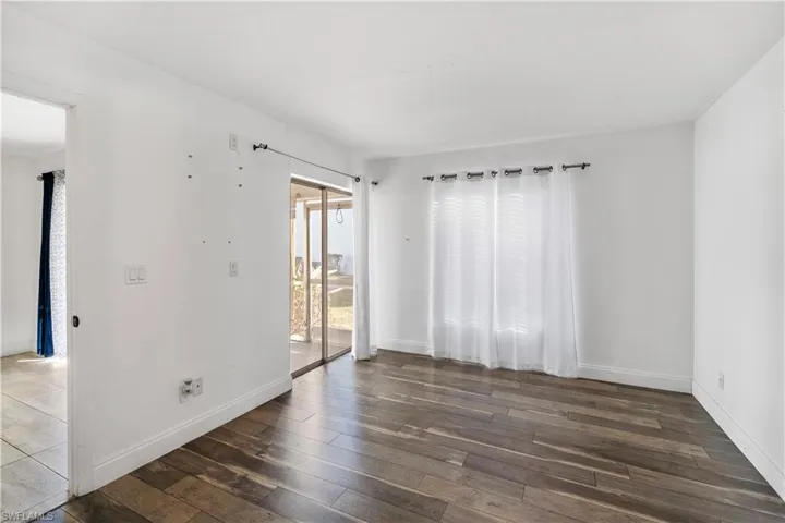 Spare room with dark wood-style floors and baseboards
