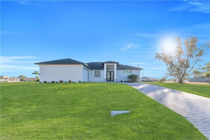 View of front of home with a front yard, decorative driveway, and stucco siding