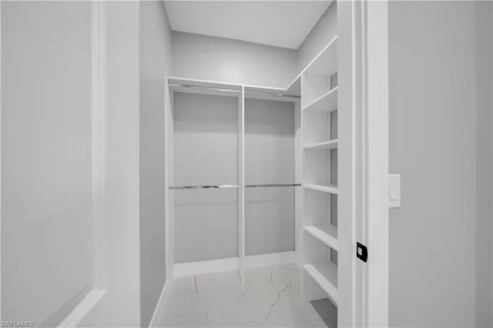 Walk in closet with light marble finish flooring