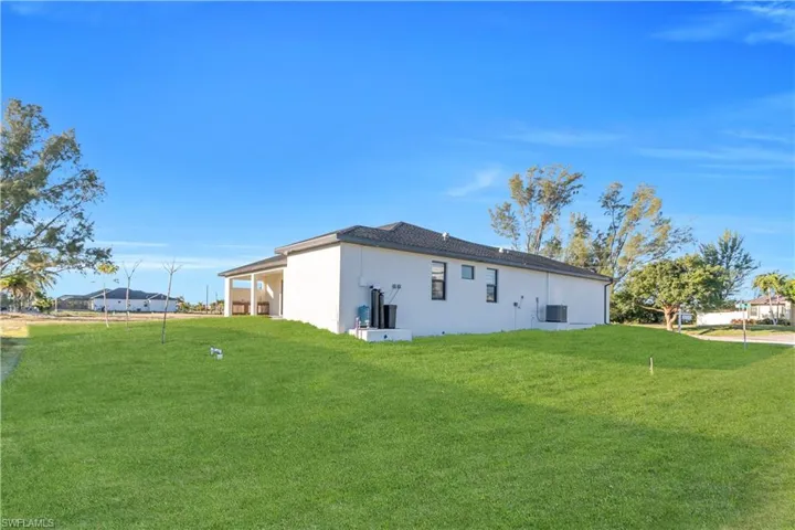 Back of property featuring a lawn and stucco siding