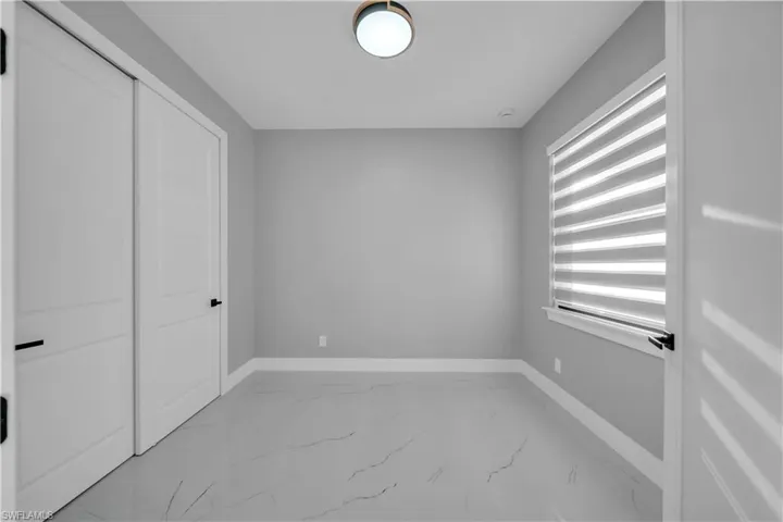 Unfurnished bedroom featuring light marble finish floors and a closet