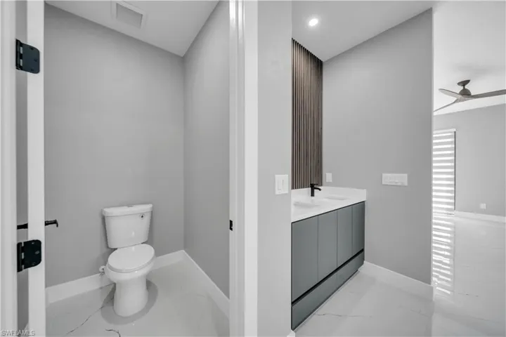 Full bathroom featuring light marble finish floors, a ceiling fan, double vanity, and recessed lighting