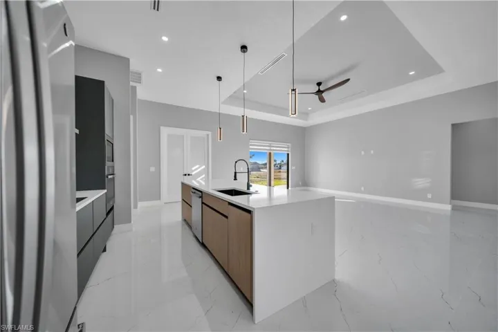 Kitchen with modern cabinets, stainless steel appliances, light stone countertops, light marble finish flooring, and recessed lighting