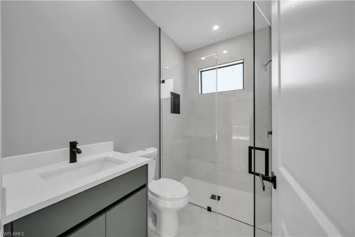 Bathroom with vanity, a marble finish shower, and light marble finish flooring