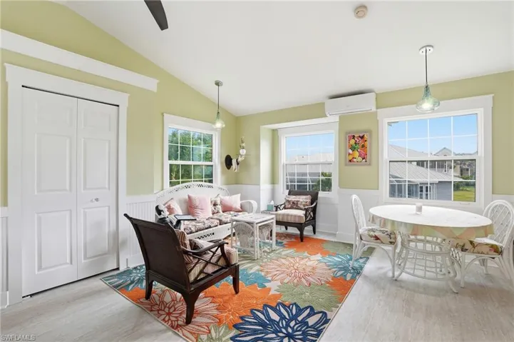 Living room featuring a wainscoted wall, wood finished floors, vaulted ceiling, and a wall mounted AC