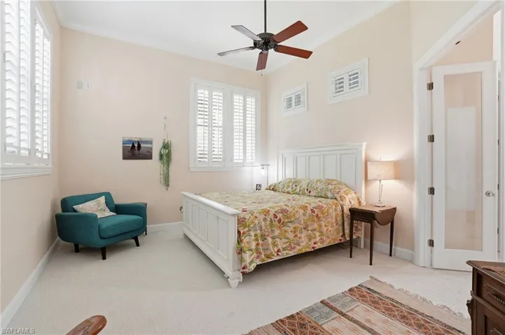 Bedroom with light carpet, ornamental molding, and a ceiling fan