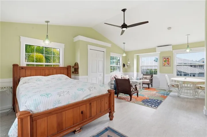 Bedroom with a wainscoted wall, a closet, wood finished floors, ceiling fan, and lofted ceiling