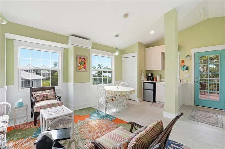 Living area featuring wainscoting, vaulted ceiling, a wall mounted air conditioner, recessed lighting, and light wood finished floors