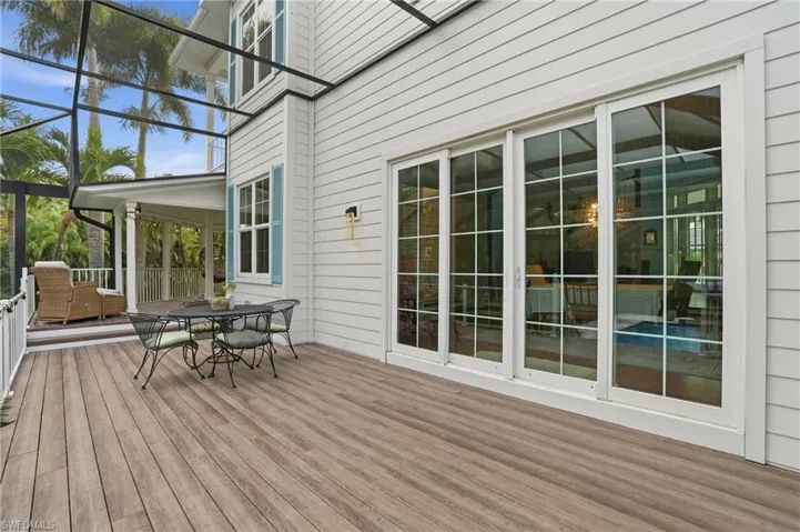 Wooden deck featuring a sunroom and outdoor dining area