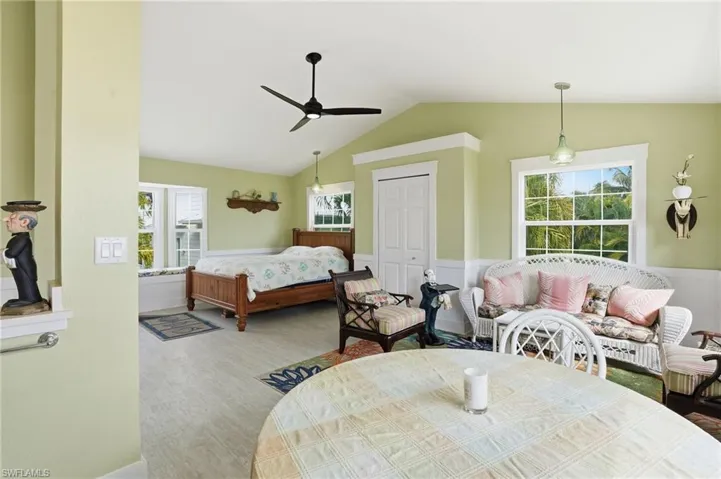 Bedroom featuring a closet, a wainscoted wall, a ceiling fan, vaulted ceiling, and wood finished floors
