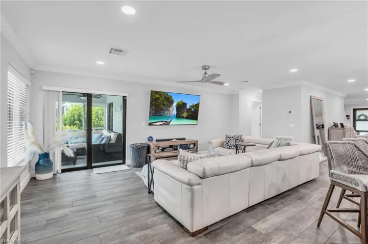 Living room featuring ceiling fan, crown molding, and wood-look tile flooring