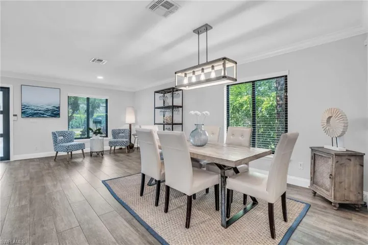 Dining room featuring ornamental molding, plenty of natural light, and coastal chandelier