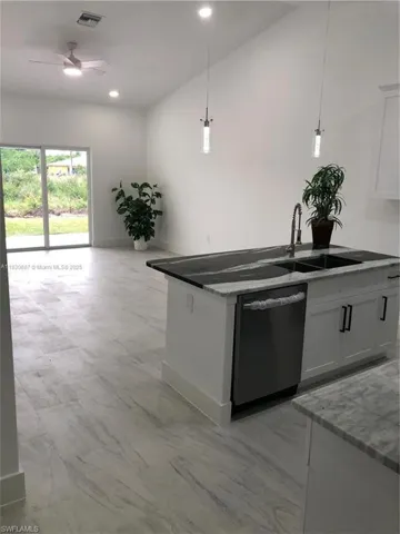 Kitchen with decorative light fixtures, dishwasher, open floor plan, white cabinets, and recessed lighting