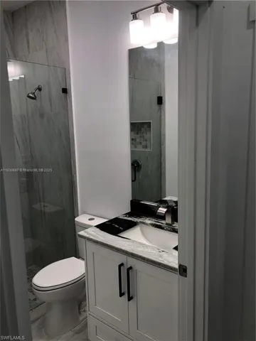 Full bathroom featuring vanity, a marble finish shower, and marble finish floors