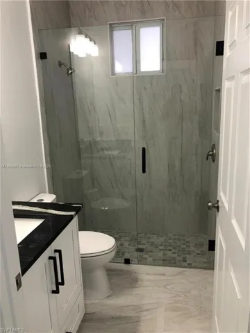 Full bath featuring vanity and a marble finish shower