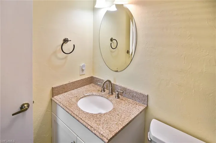 Half bathroom with a textured wall and vanity